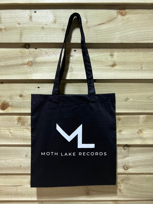Black tote bag with Moth Lake Records logo on a wooden background