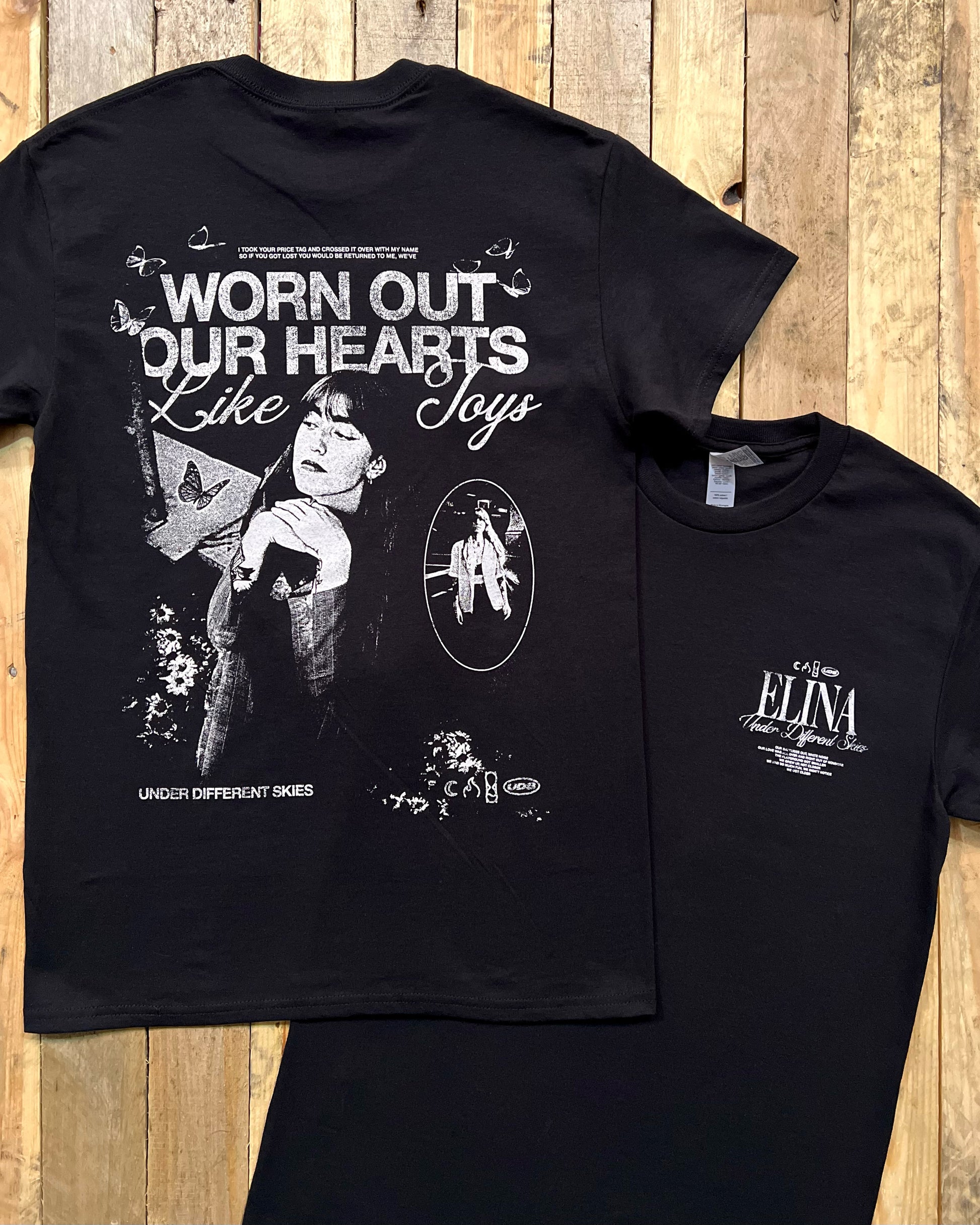 Black t-shirt with large screen printed design on the back and small print on the front on a wooden surface